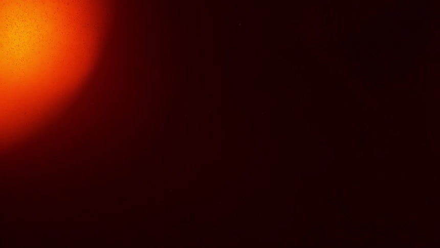A black screen followed by an orange light which illuminates the screen into orange and then fades back to black