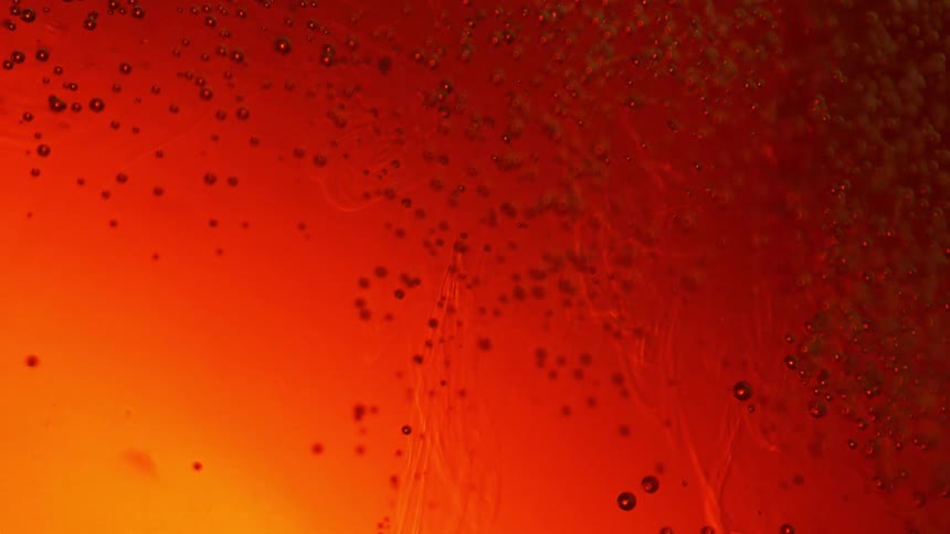 Air bubbles dipping and rising on a liquid with red and yellow backlight