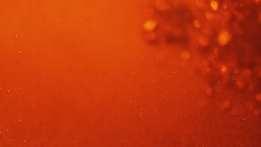 Red liquid is moving creating bubbles in changing light going from black to red to orange