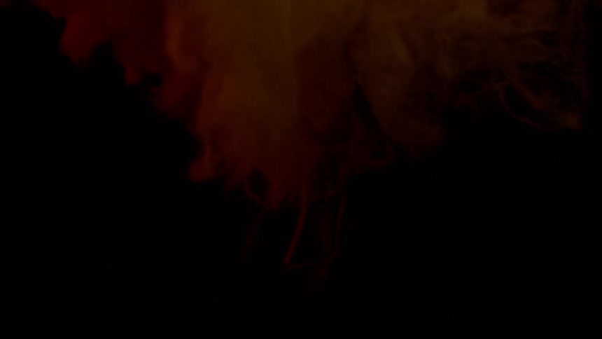 Burst of white bubbles flowing up and down a vat of liquid under a red light
