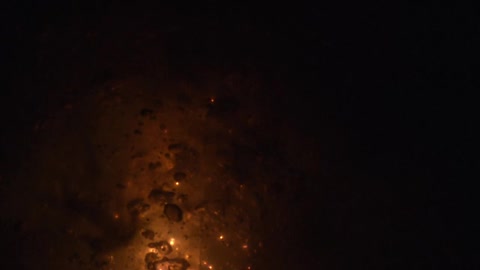 Smoke rises from the burning flames at night