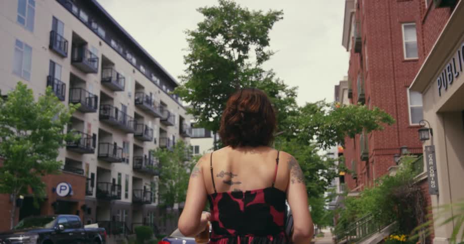 A woman walks down a sidewalk in a neighborhood