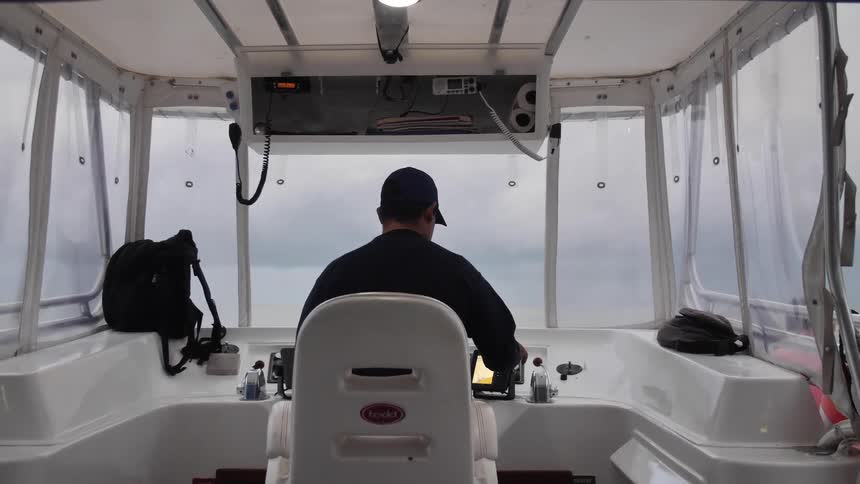 A man sits in a chair and drives a boat