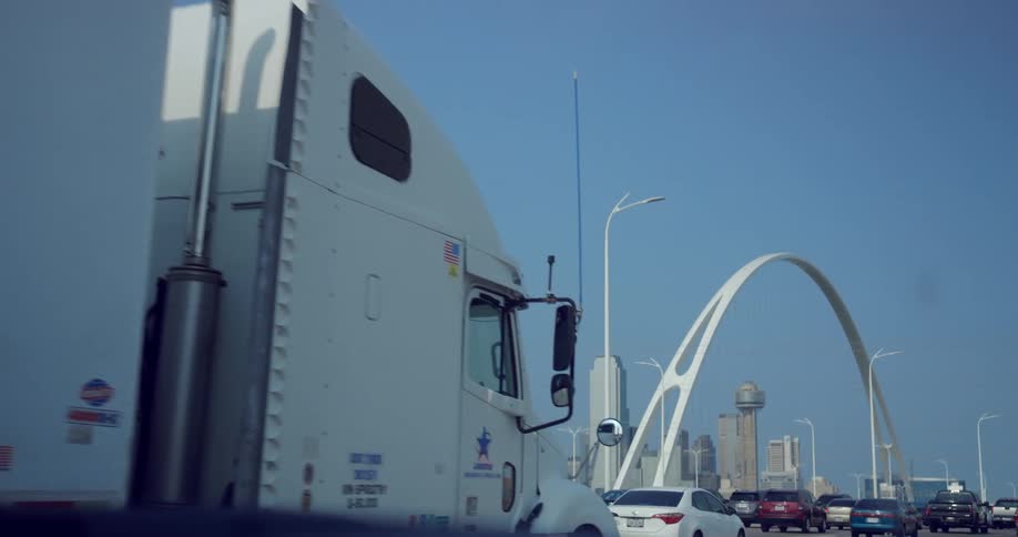 A road with vehicles with an arch a city skyline the sky and clouds in the background