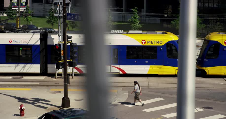 A person walks across a city intersection as a large public bus passes by