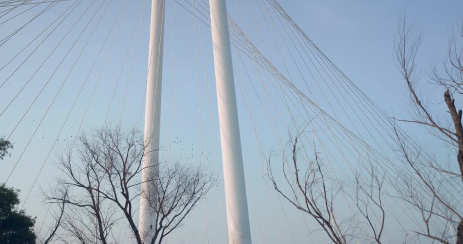 White metallic columns of a suspension bridge against a blue sky
