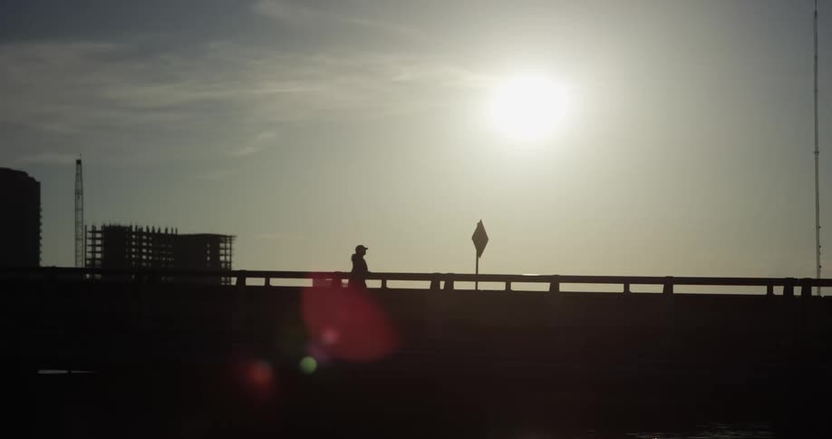 A woman jogs across a bridge in a city during the day