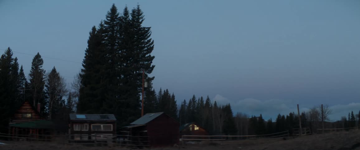Cabins with a wooden fence with trees the sky and clouds in the background