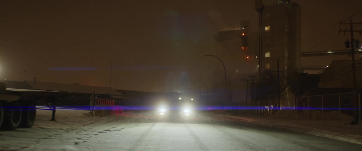 A car drives down the road as it snows