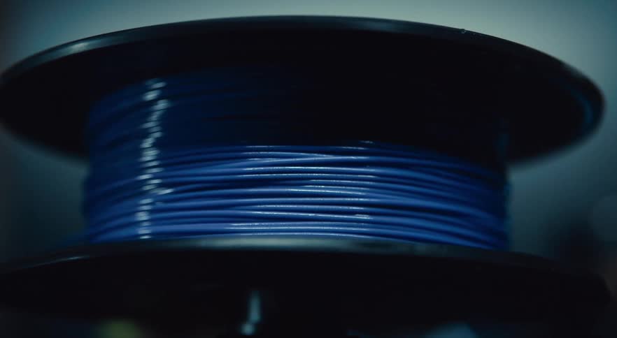 A spool of blue wire is moving in a circular fashion