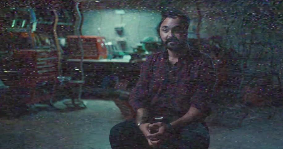 Man sitting inside of a workshop talking while screen glitches to a computer program
