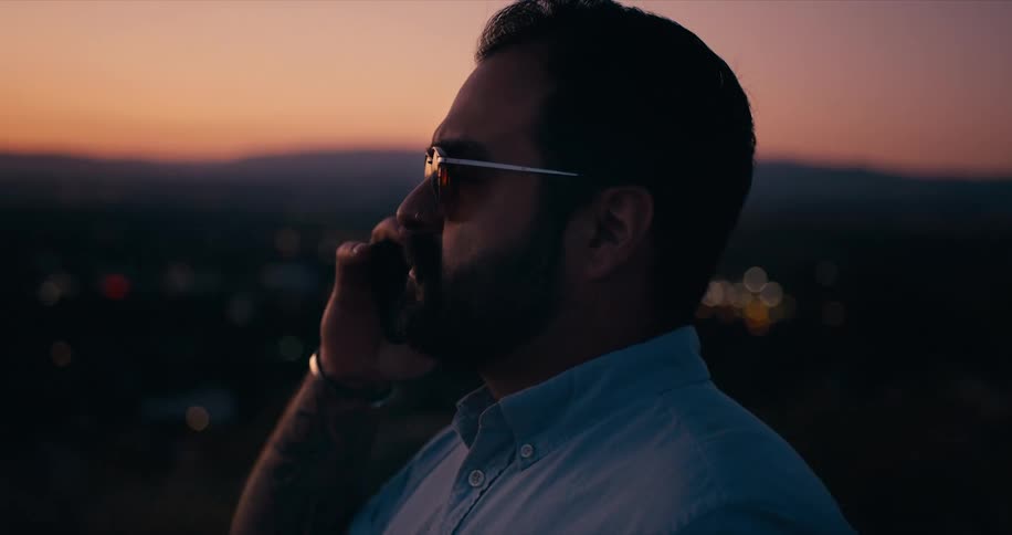 A man is talking on a cellphone at dusk