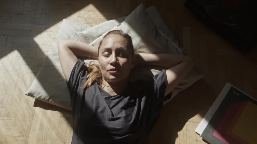 Woman lies down on pillow on floor