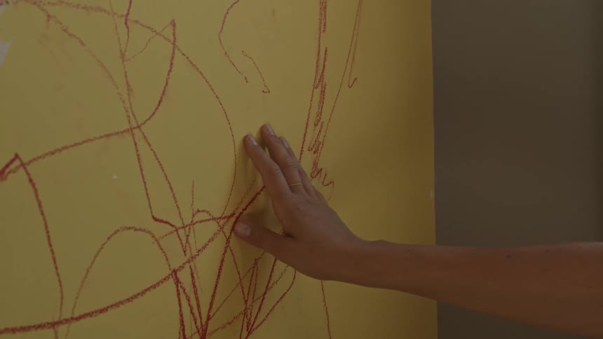 A hand is moving down a yellow wall with red markings