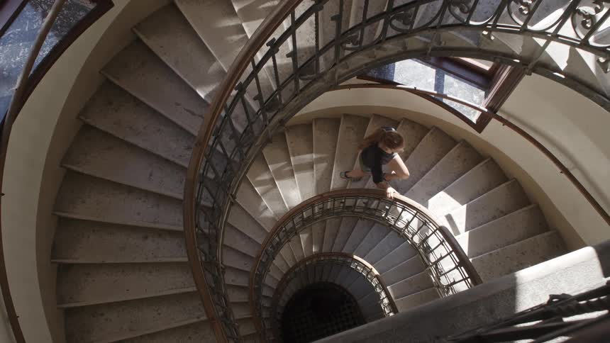 A woman walking up a large spiral staircase