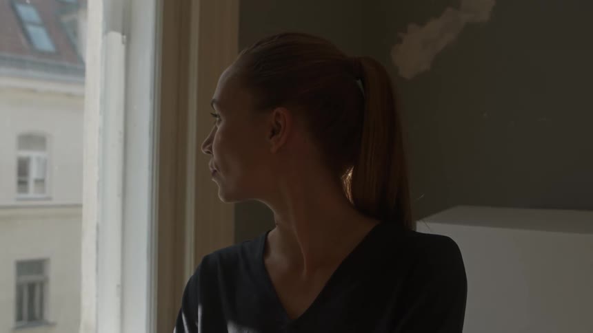 A woman is looking out a window during the day