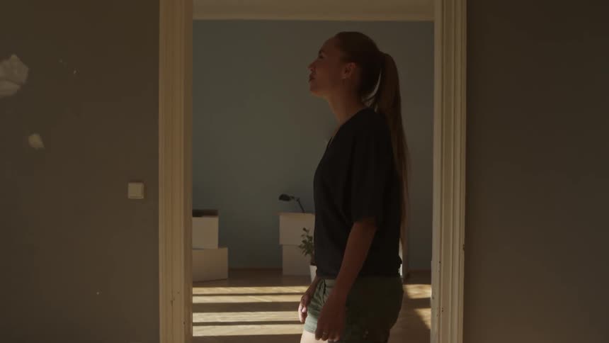 A woman stands in the doorway in front of a room with several moving boxes
