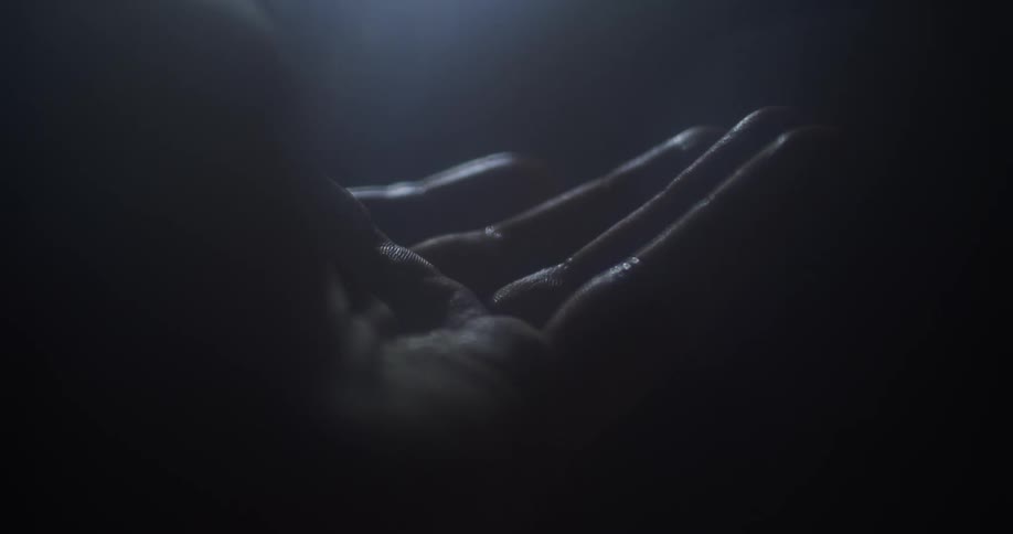 Closed hand in a dark room opening
