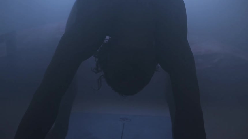 Man in low light does a backbend in front of a window where sunlight comes in and you can see a building