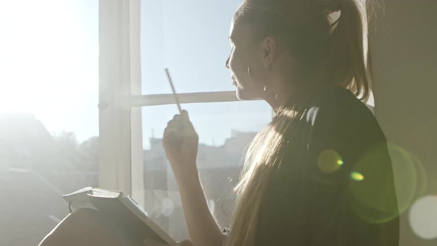 A woman is sitting by a window during the day