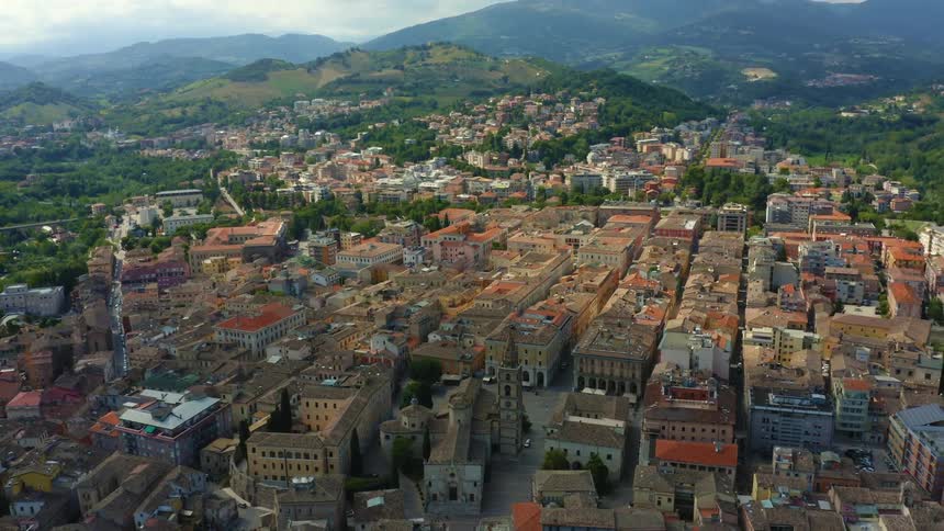 Church sits next to buildings with courtyards in town stretching toward mist covered hills and mountains on horizon
