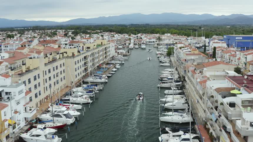 An aerial view of hotels on the water with boats parked and sailing
