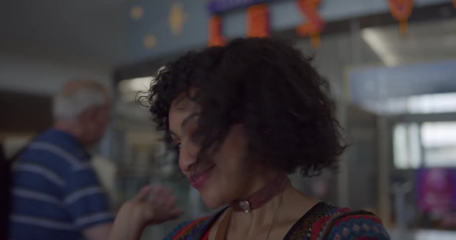 A young woman smiles and playfully poses for the camera in a public place