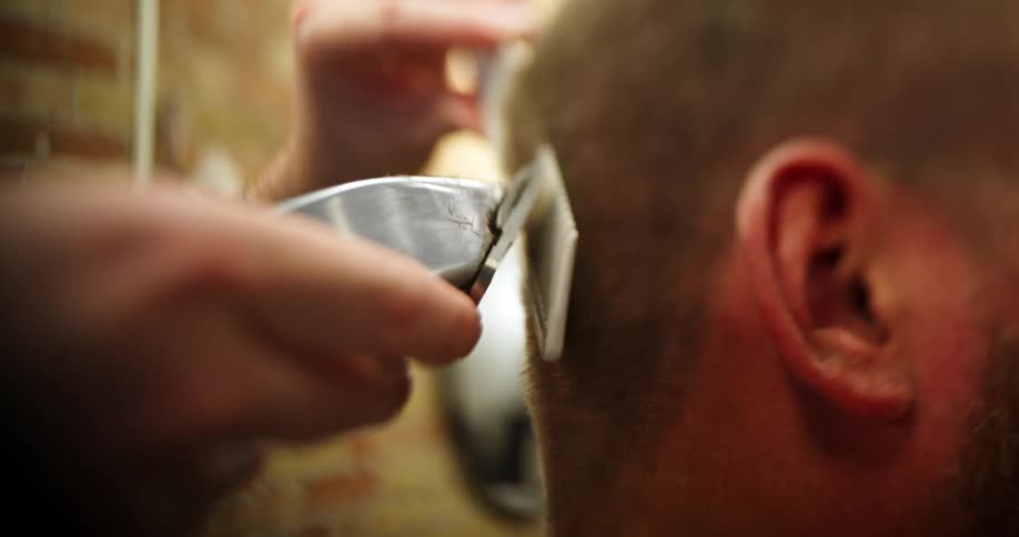 A barber shaves a mans hair