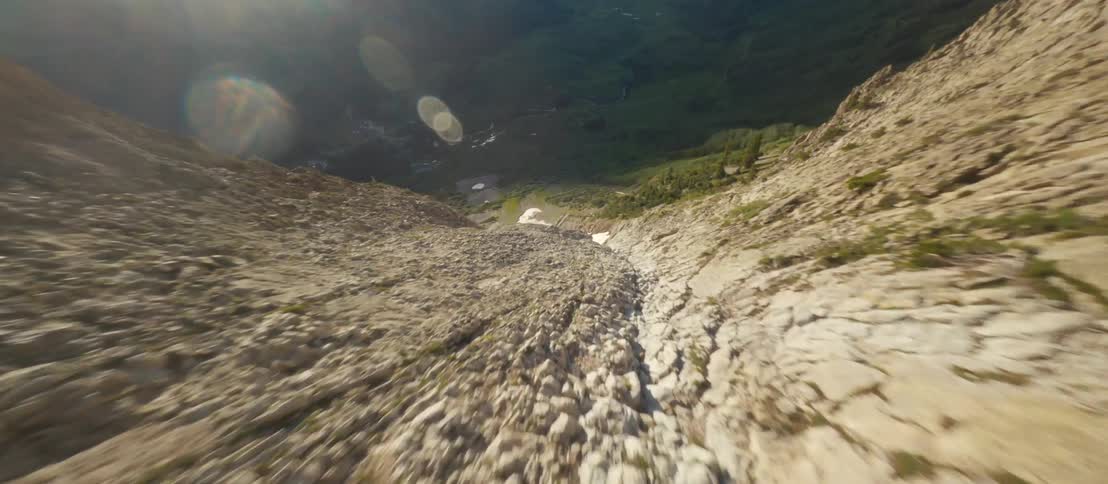 Slope leads to snow patch that leads to dirt trail toward mountain