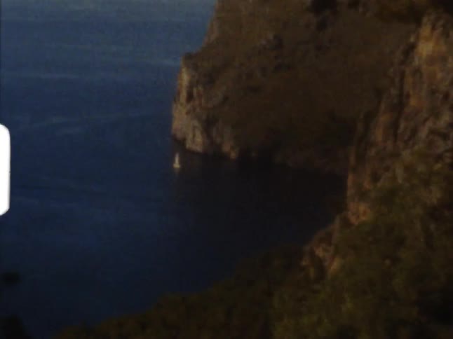 A sailboat on a coast next to a cliff on 8mm