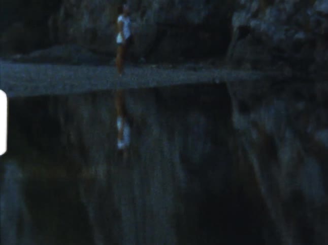 A person standing next to a lake near rocky cliffs on 8mm