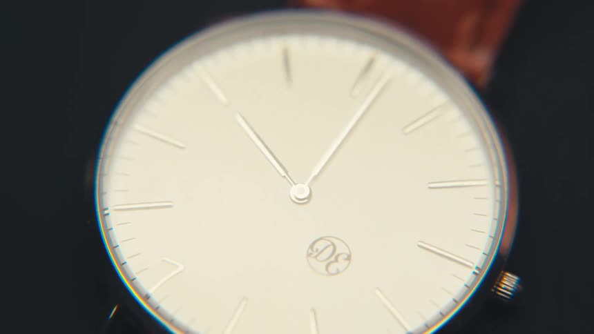 A wristwatch with a leather strap on a black surface
