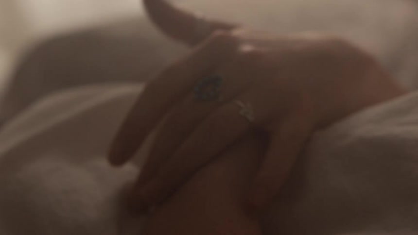 Human stroking their hands together in their bed