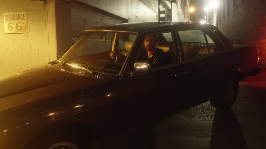 A man sits in a parked car coming from a city garage