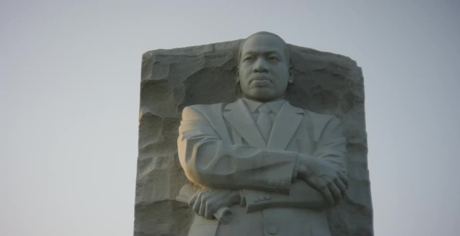 Martin luther king stands with his arms crossed in a national monument