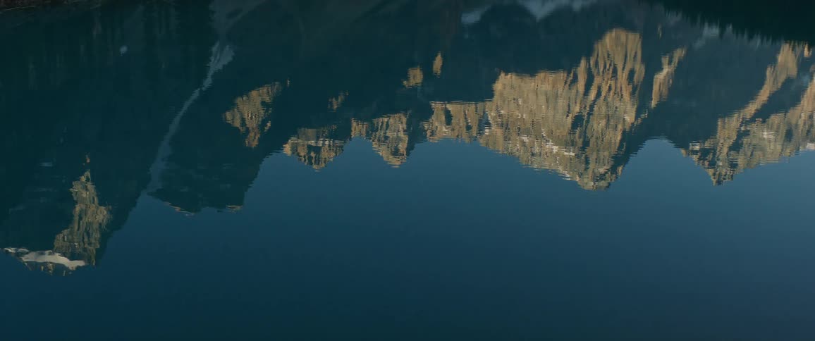 A calm lake reflects the barren mountain range above it