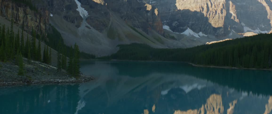 A lake with a mountain range trees and the sky in the background
