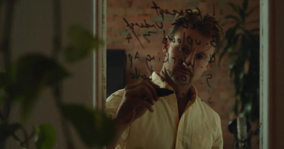 A man writing on a mirror with a marker