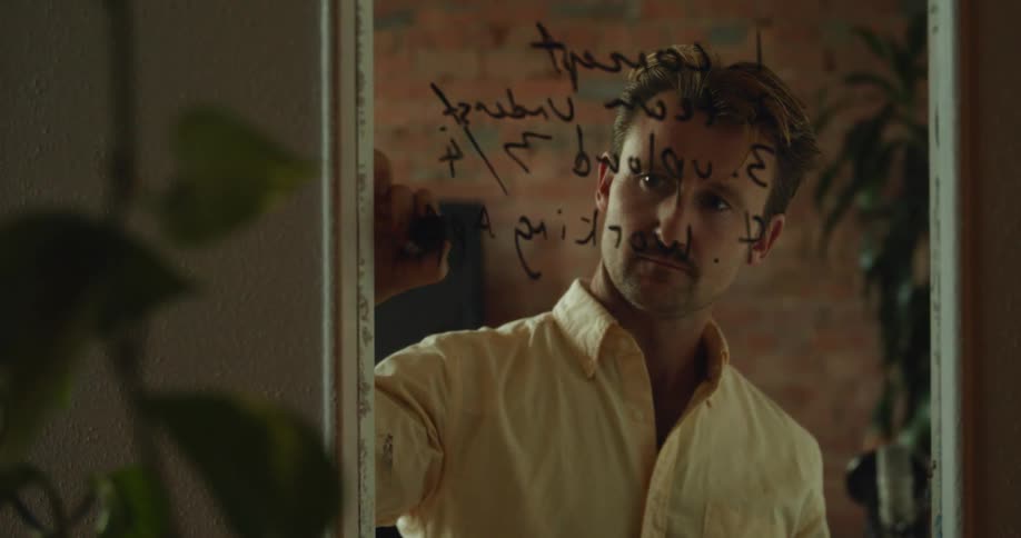 A man writes a message on a mirror in a home