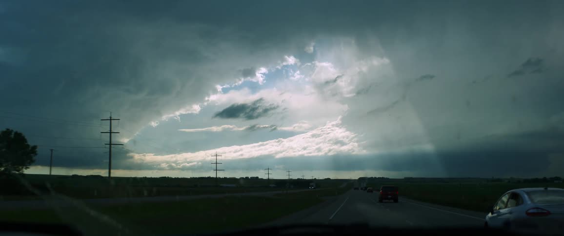 Wipers clean the windshield of a car driving down a highway on an overcast day