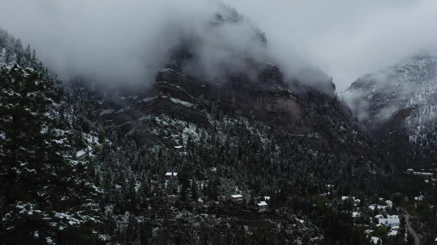 Aerial view of fog covering a forest and mountain range
