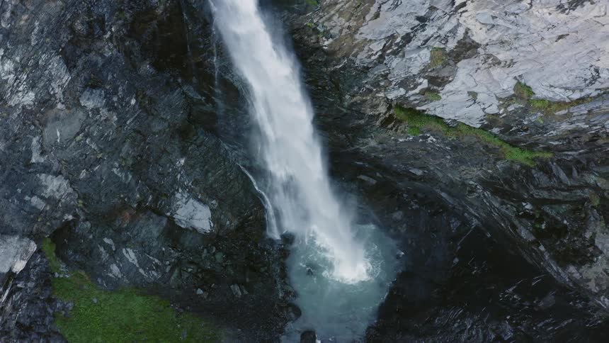 A cliff with a waterfall and algae