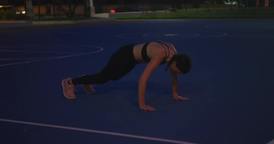 A woman is performing exercises outdoors at nighttime