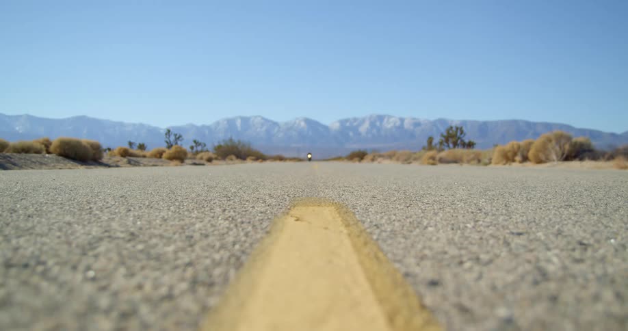 A person rides a motorcycle on a quiet rural road