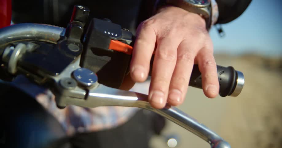 A man is getting on a motorcycle outdoors during the day