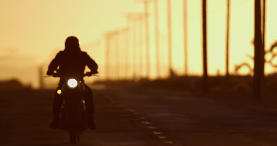 A person is riding a motorcycle on a road at dusk