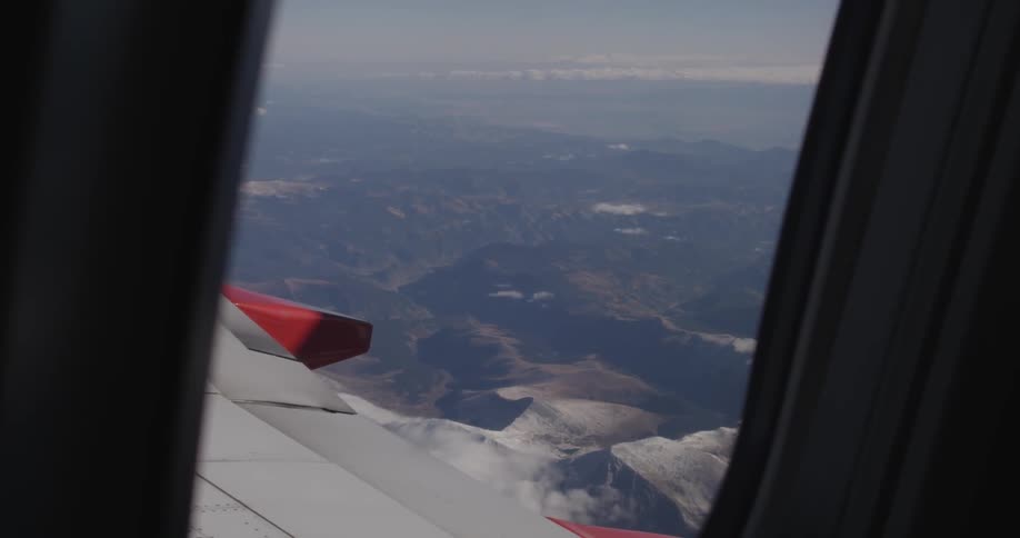 A mountain range is seen through the window of an airplane