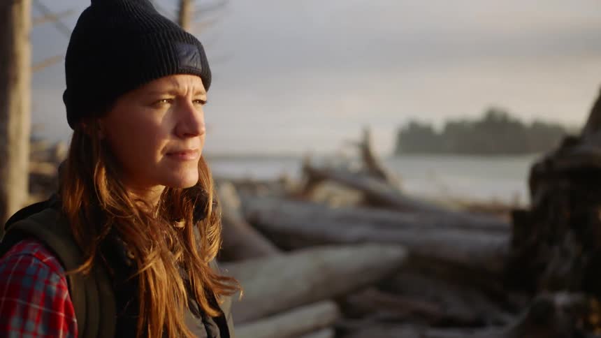 A woman is hiking outdoors by the coast