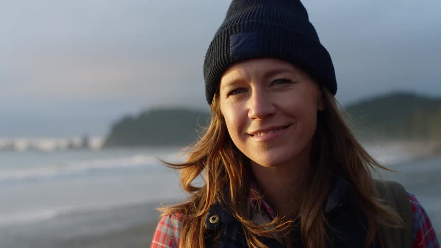 A woman with brown hair and wearing a beanie smiles at the camera