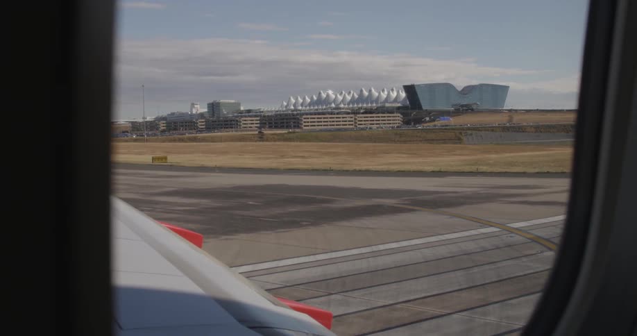 A view of cars and buildings on a street at the edge of an airport